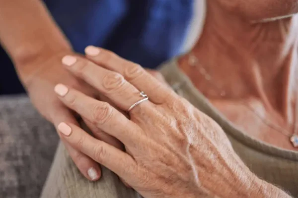 Older woman receiving comfort and emotional support from a carer at home.